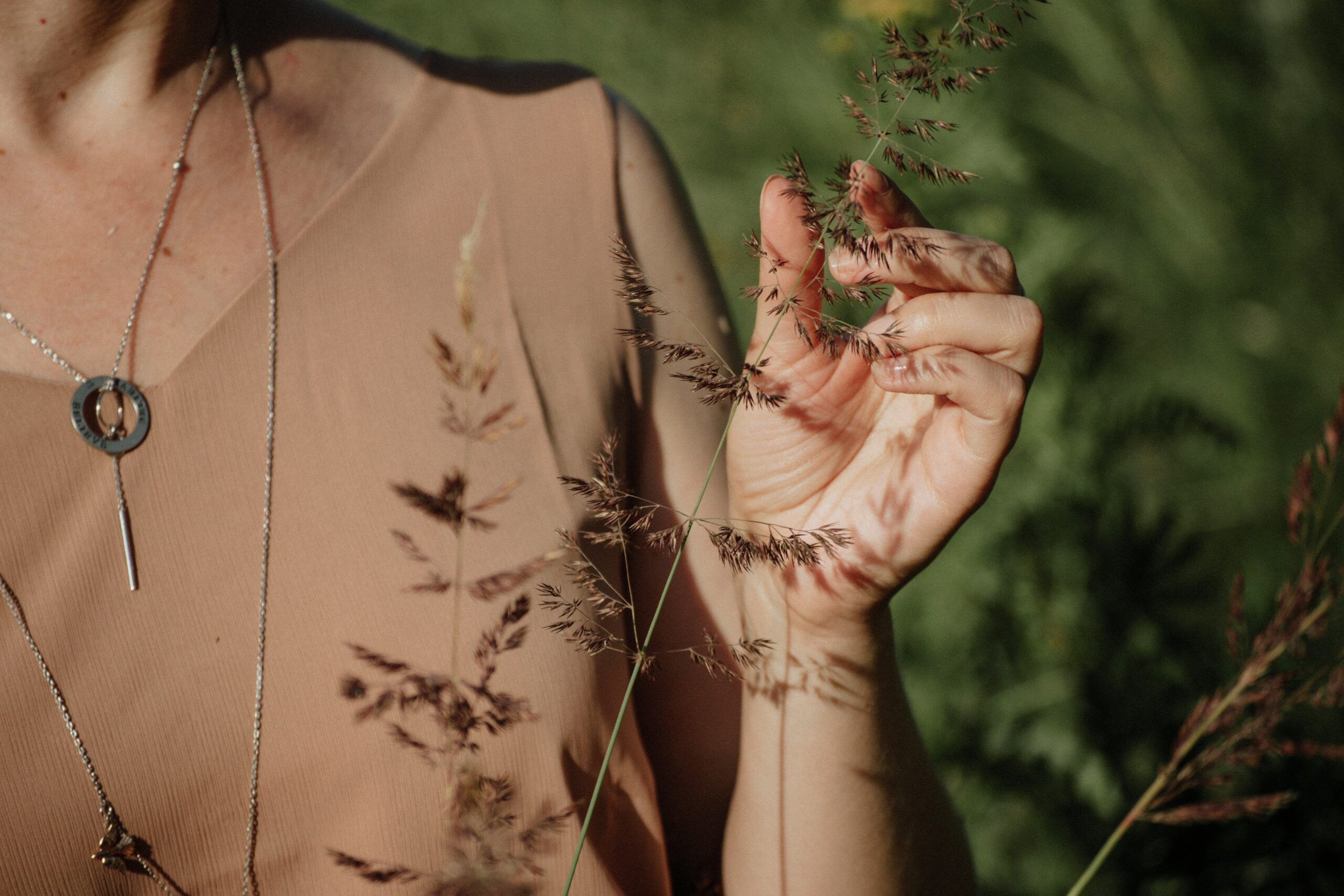 Close-up photo of hands holding acupuncture needles beside herbs